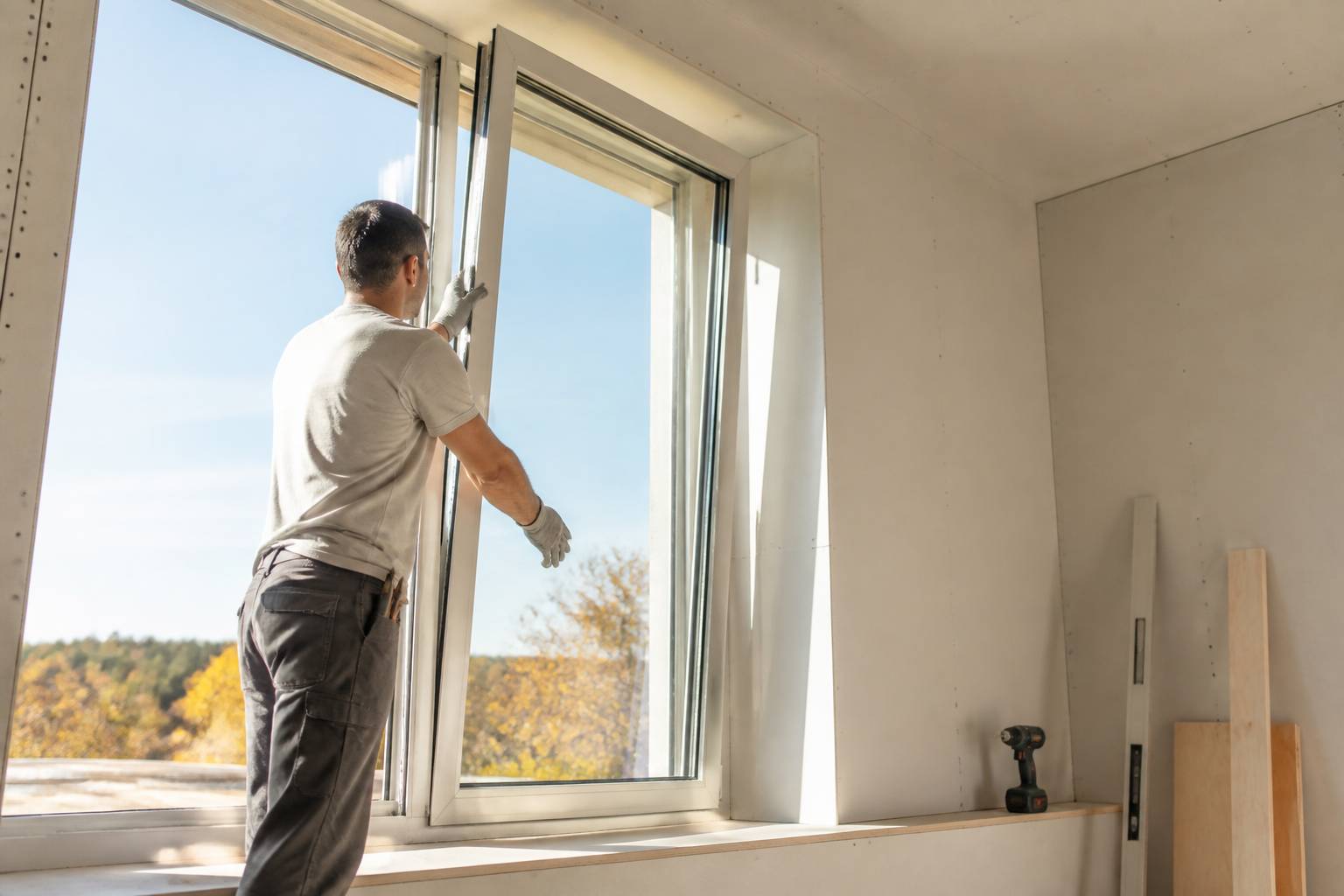 Artisan posant une fenêtre à double vitrage dans une embrasure éclairée